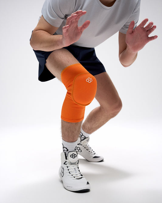 Person wearing an orange knee pad on a white background