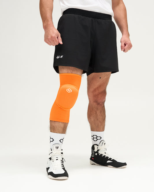 Person wearing an orange knee pad on a white background