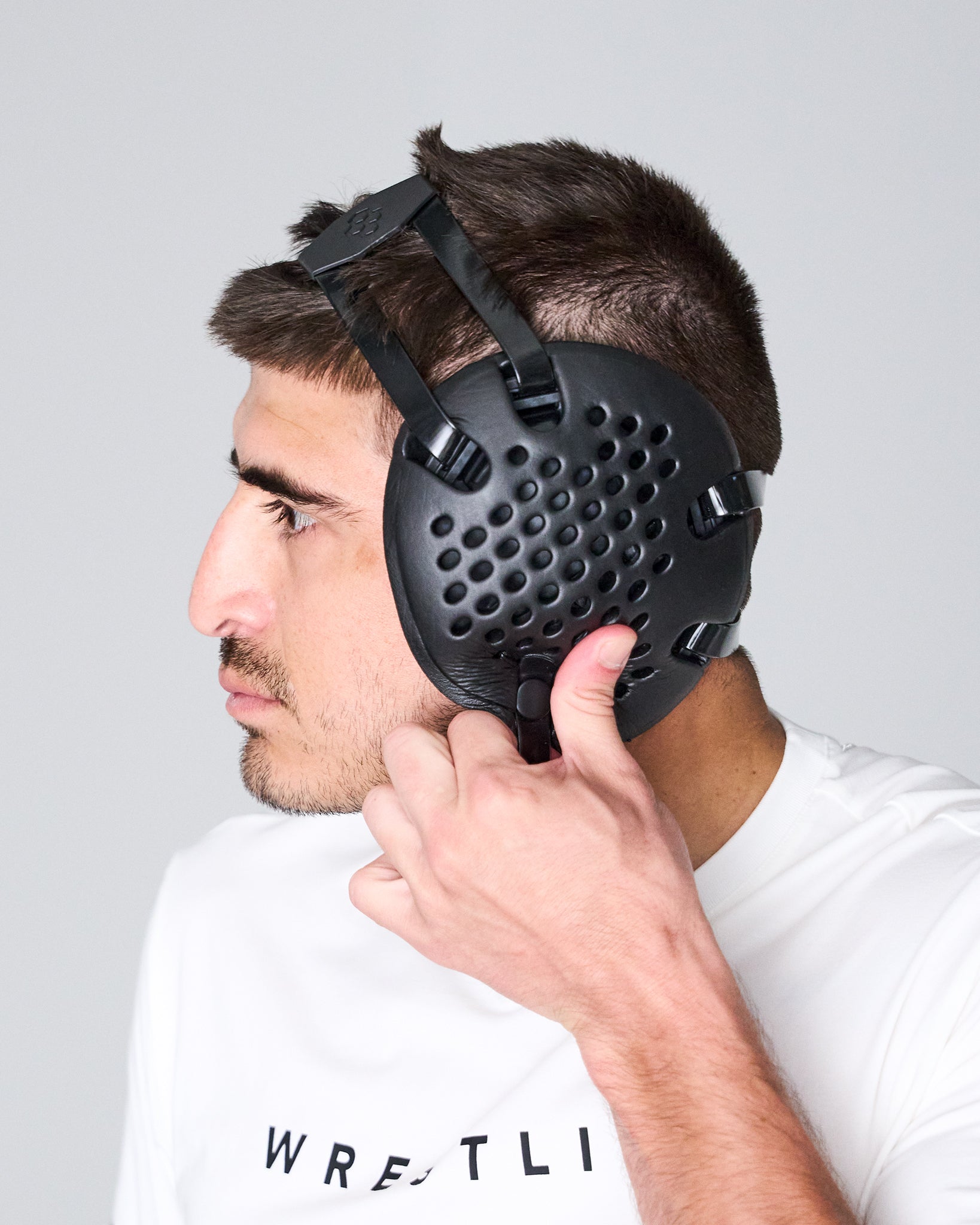 Person wearing a black protective headgear against a gray background
