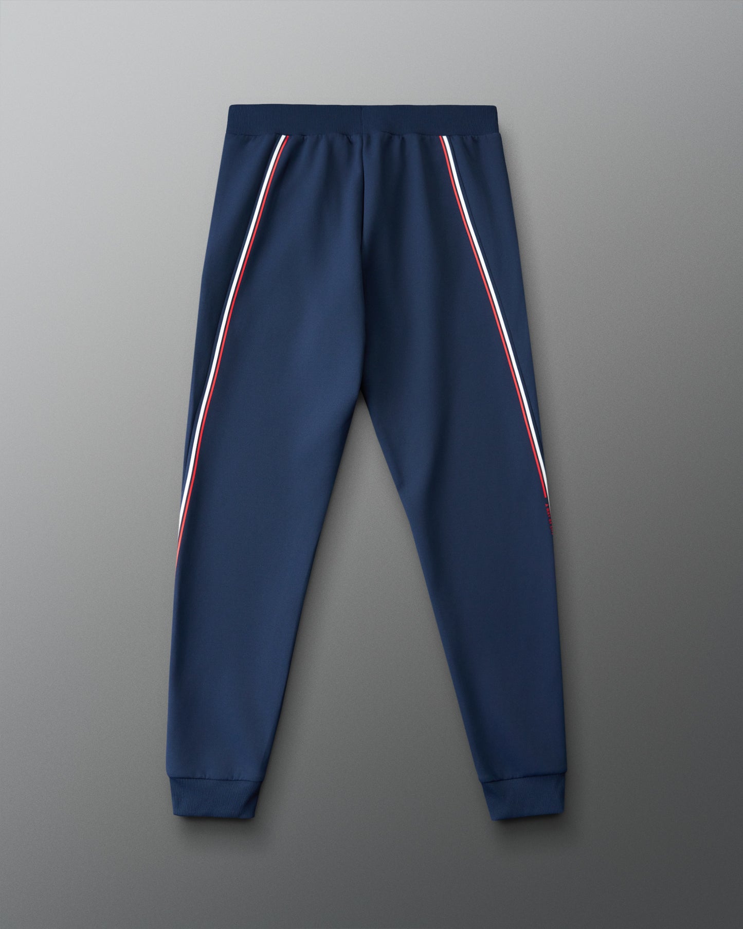 Navy blue jogger pants with red and white stripes on a gray background