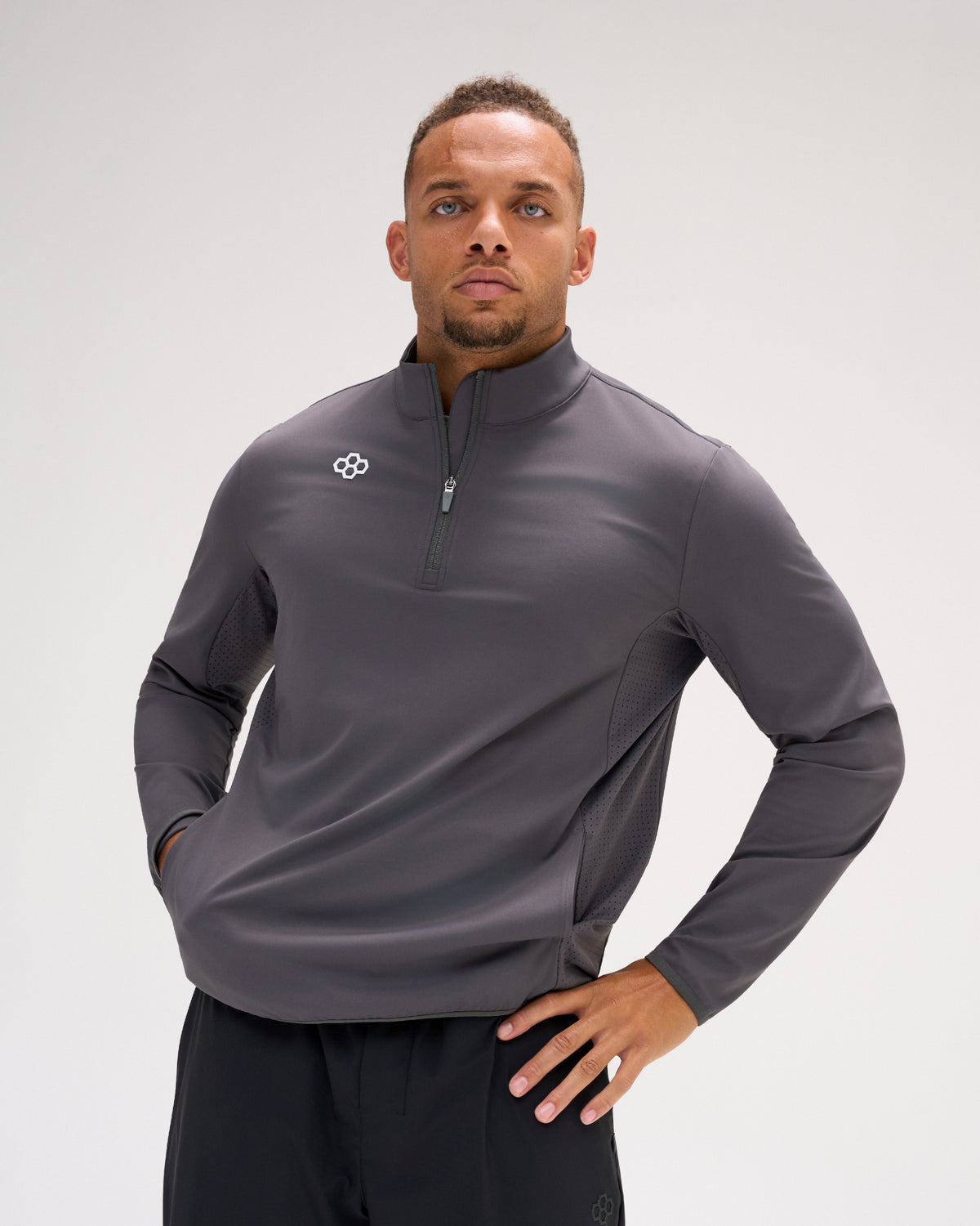 Man wearing the carbon RUDIS Victory 1/4 Zip performance pullover with RUDIS chest logo, quarter-zip collar and ventilated side panels.