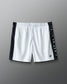 White shorts with black side panels and branding on a gray background