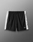 Black shorts with white side panels and branding on a gray background