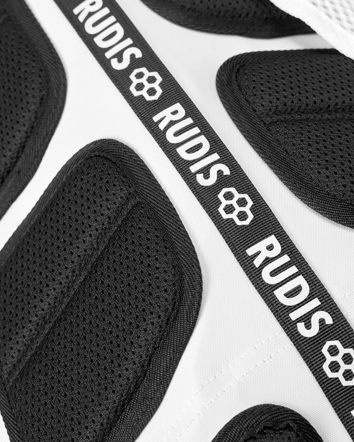 Close-up of the RUDIS Superman Double Cinch backpack showing breathable black mesh back padding and repeating RUDIS logo webbing.