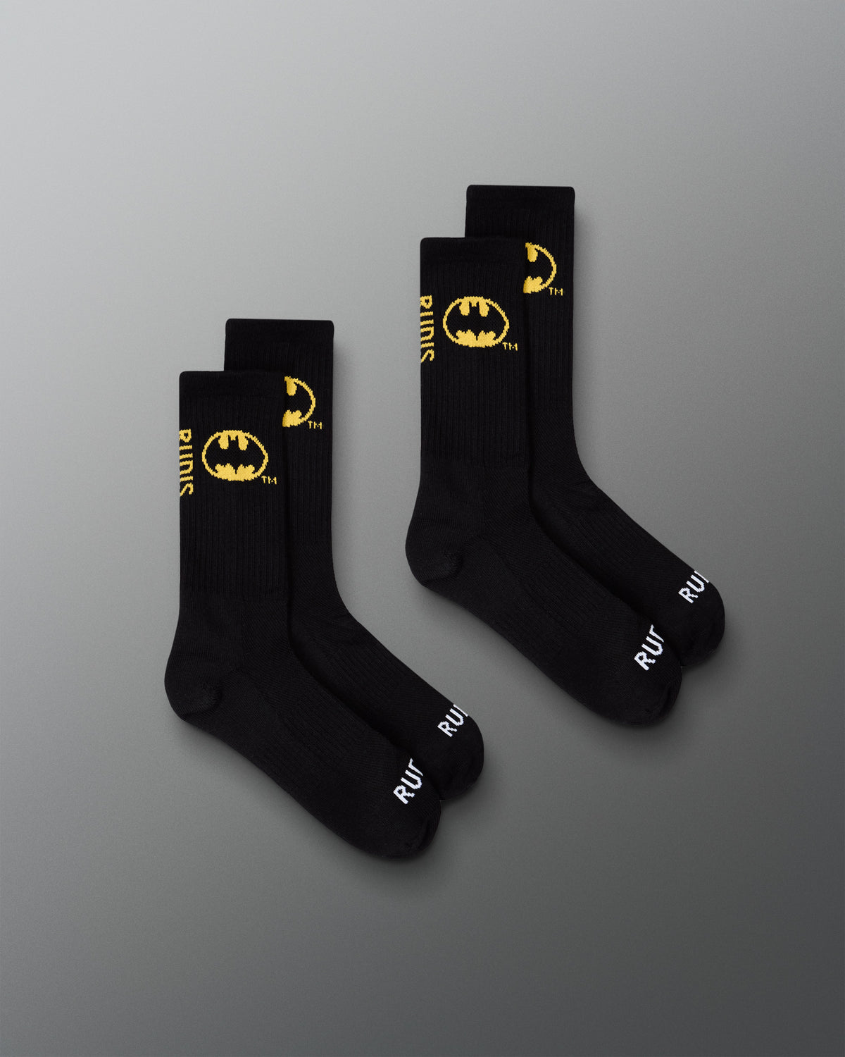 Two pairs of black RUDIS Batman Cushion Crew Socks featuring yellow Batman logos and white RUDIS branding.
