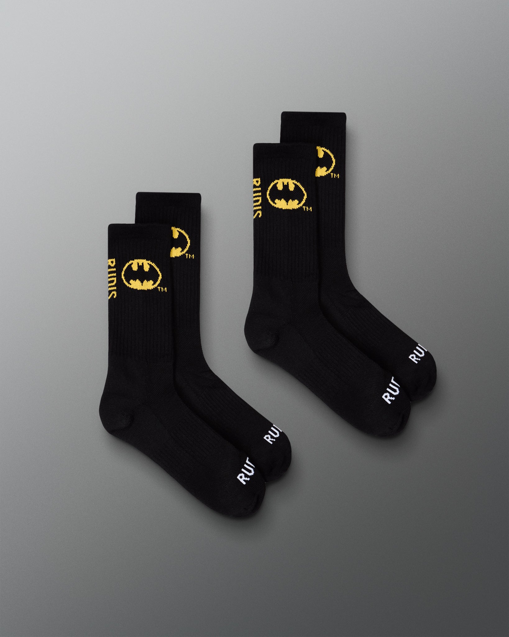 Two pairs of black RUDIS Batman Cushion Crew Socks featuring yellow Batman logos and white RUDIS branding.