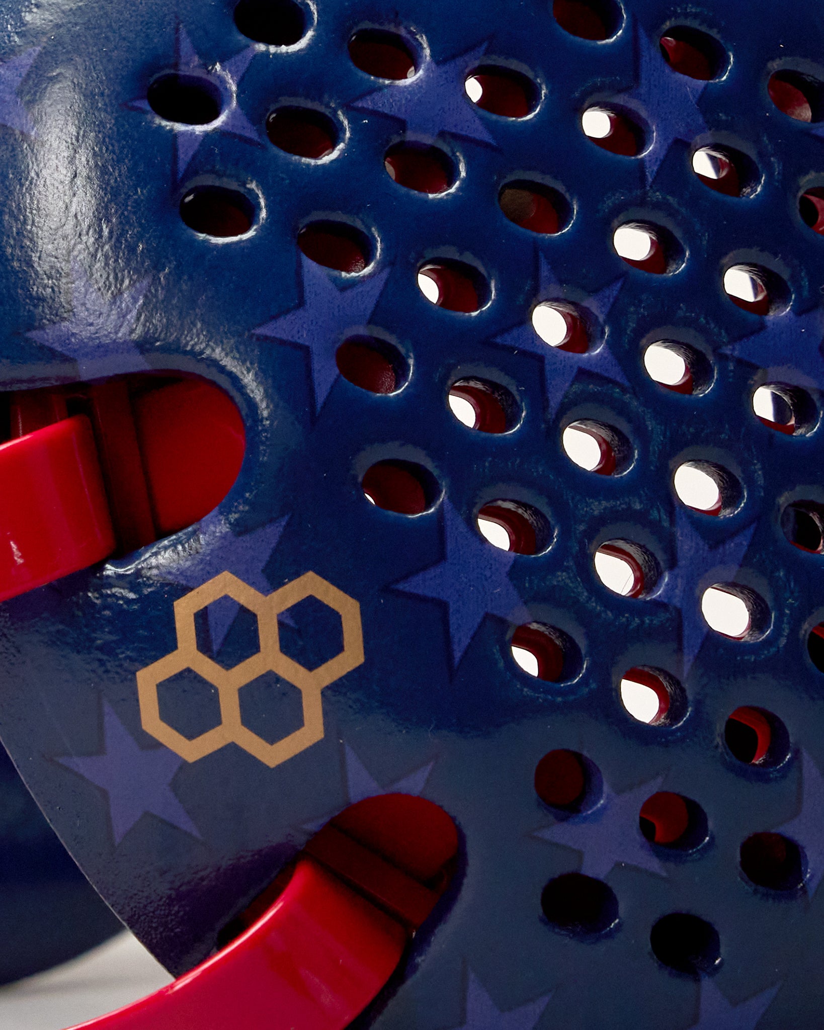 Close-up of RUDIS Wonder Woman Elite Airflow Wrestling Headgear showing perforated navy blue ear guard, subtle star graphics, gold RUDIS logo and red strap.