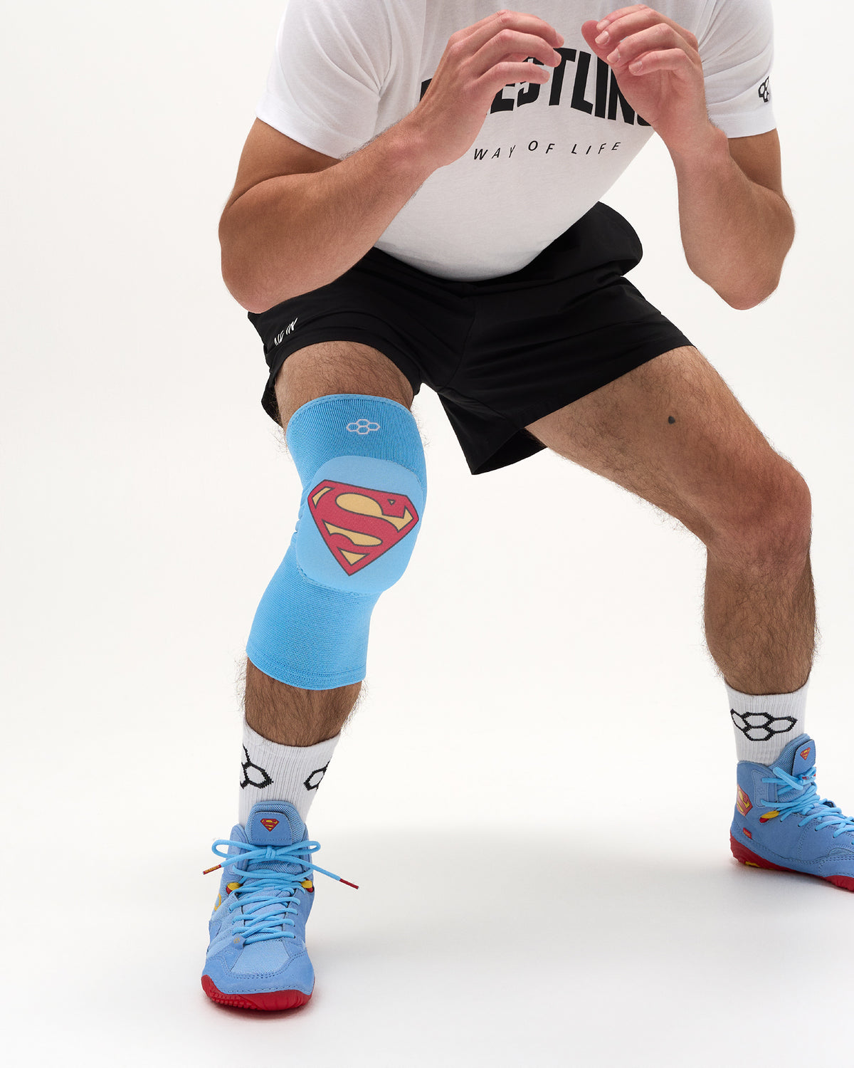 Wrestler training in a blue RUDIS Superman Cushion Kneepad with Superman shield graphic and matching wrestling shoes.