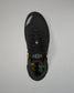 A black wrestling shoe shown from a top-down view on a neutral gray background. The shoe features a black mesh upper, black laces, a gray geometric logo on the tongue, and a colorful patterned lining visible at the collar.