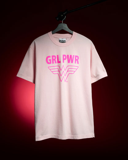 RUDIS Wonder Woman Girl Power Relaxed Cotton T-Shirt in washed pink, featuring a bold hot pink GRL PWR graphic and Wonder Woman logo, displayed on a hanger against a red background.