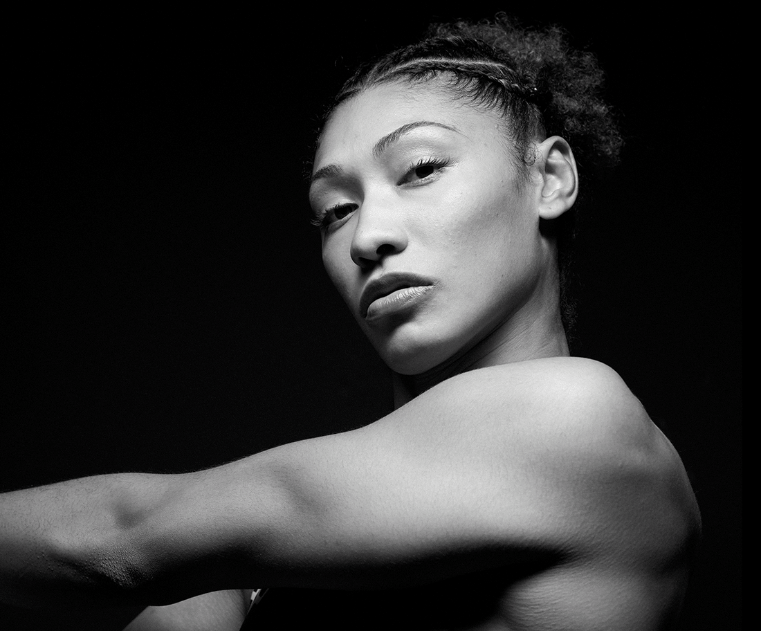 Black and white GIF of a Team USA women’s wrestler in RUDIS gear, shifting from a powerful pose to an intense close-up, highlighting strength, focus, and determination in Olympic wrestling.