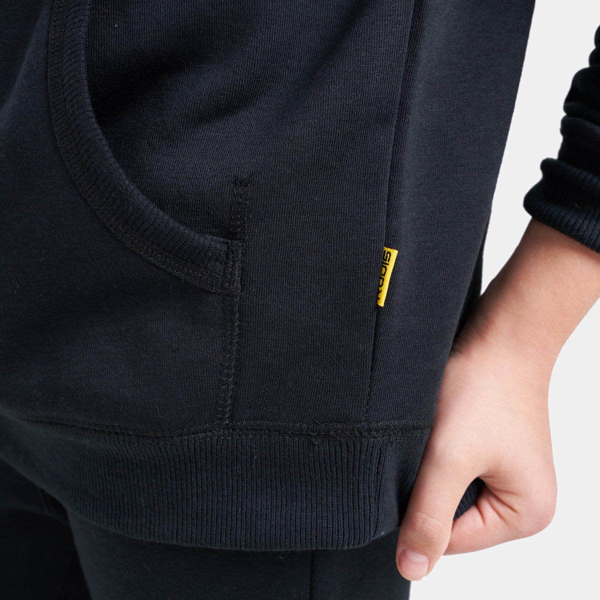 A close-up view of a black hoodie showcasing its smooth fabric a front pocket and a small yellow tag highlighting the design details
