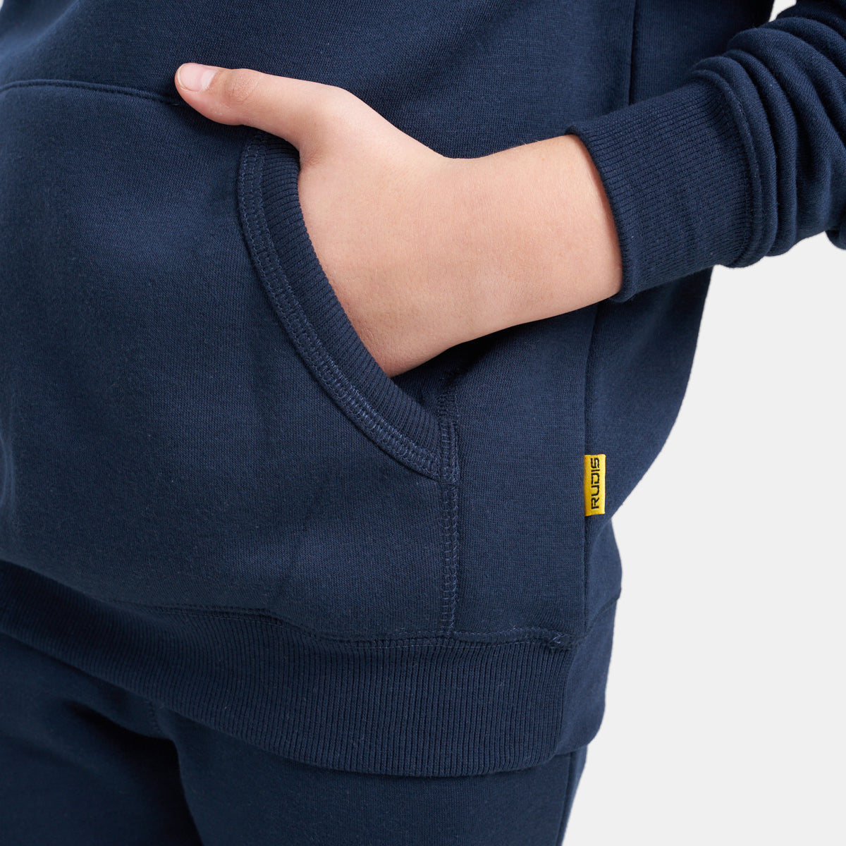 A close-up view of a childs hand resting in the pocket of a navy blue sweatshirt highlighting its soft texture and casual style