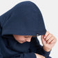 A close-up of a child wearing a navy blue hoodie with a hood drawn over their head looking down with a thoughtful expression