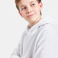 A young boy with a playful expression is wearing a white hoodie featuring a subtle hexagonal logo on the sleeve against a light gray background