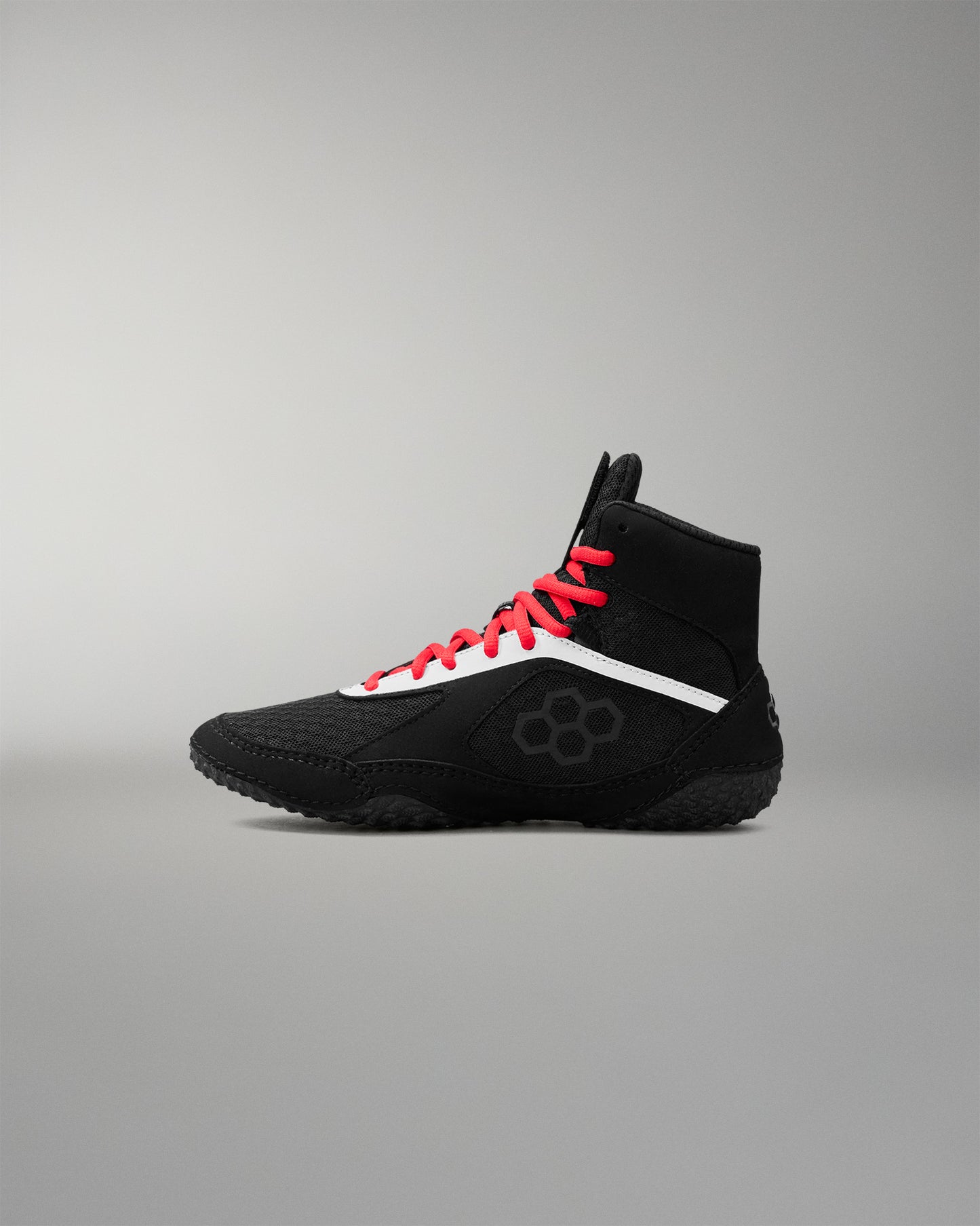 Black wrestling shoe with red laces on a gray background