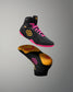 Black wrestling shoes with pink laces and yellow sole on a gray background