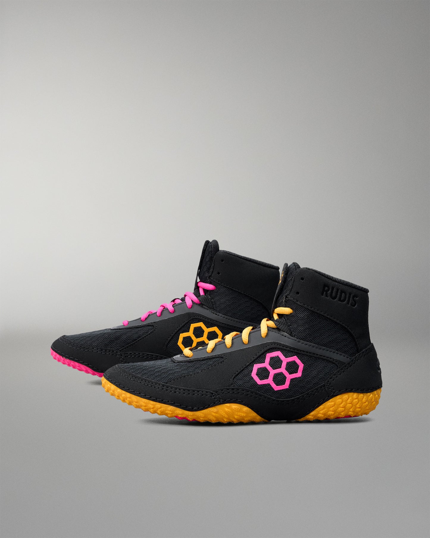 Black wrestling shoe with pink and yellow accents on a gray background