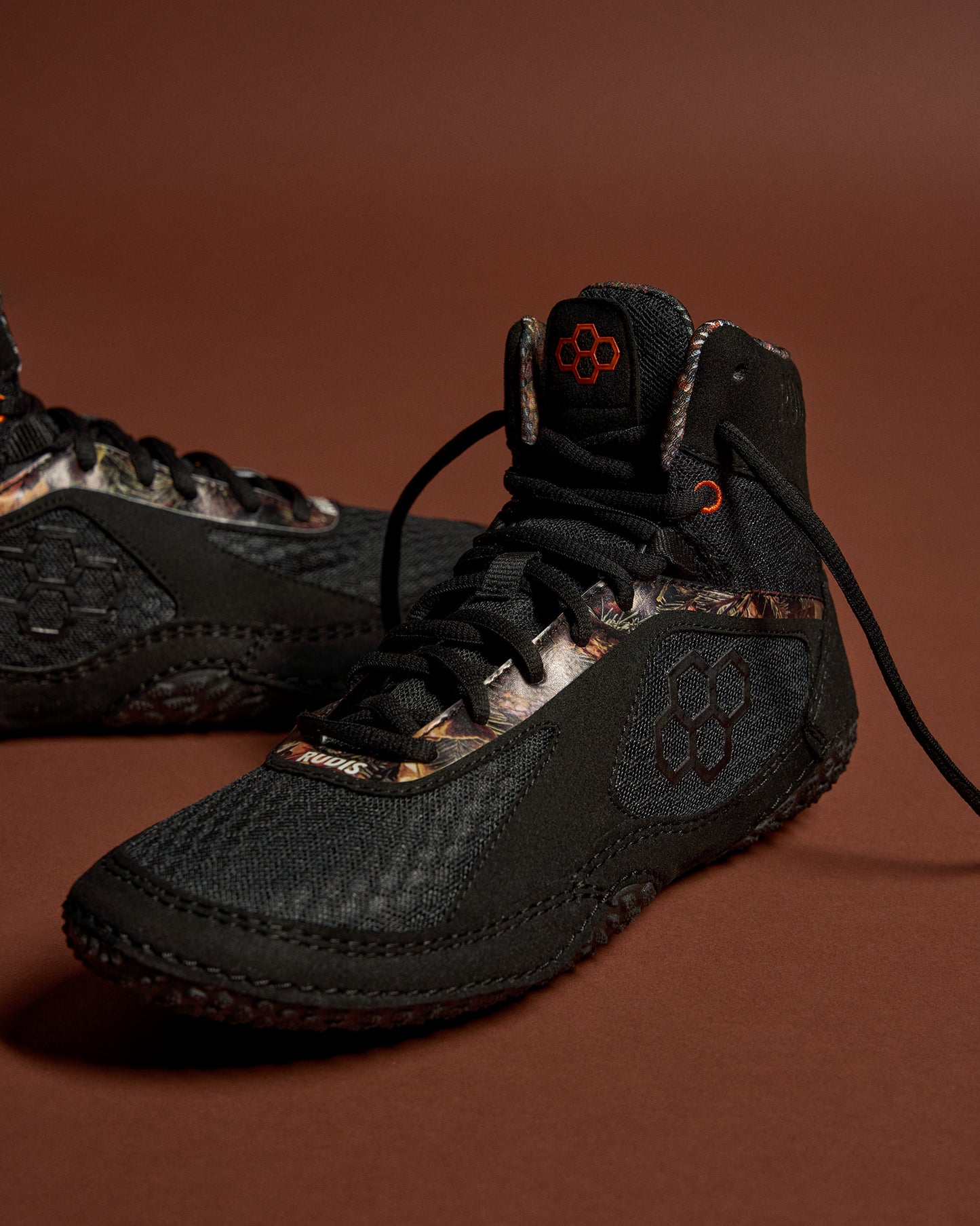 Black high-top sneakers with camouflage pattern on a brown background