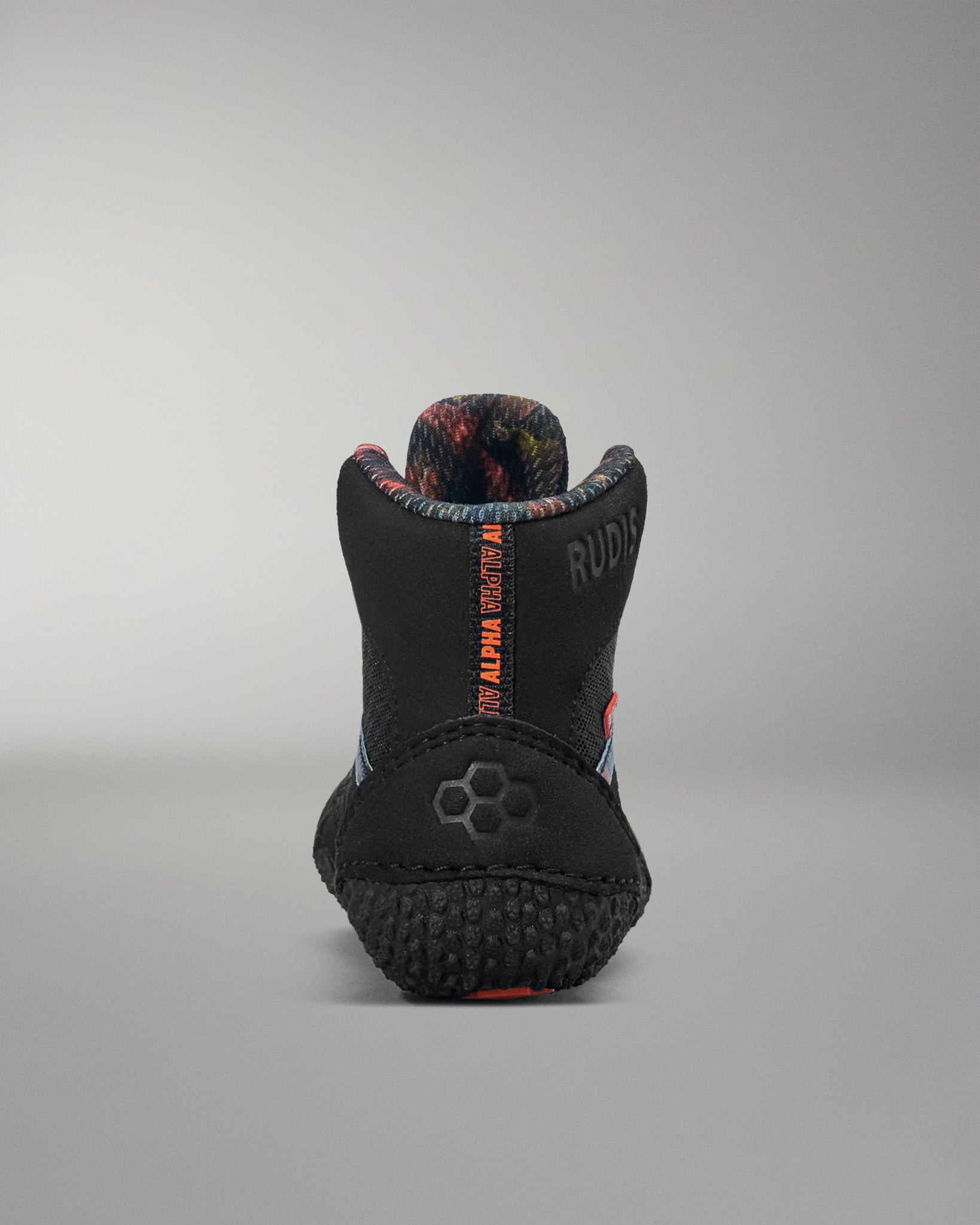 Black wrestling shoe with red and blue accents on a gray background