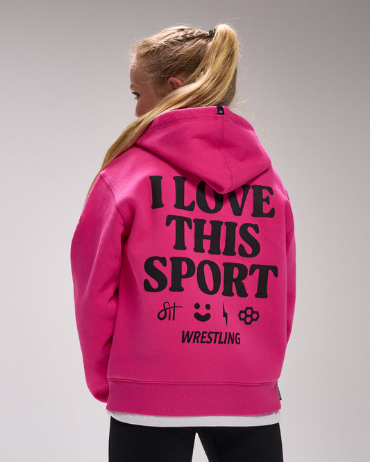 Youth athlete wearing RUDIS hot pink comfort fleece hoodie with bold “I Love This Sport” wrestling back graphic