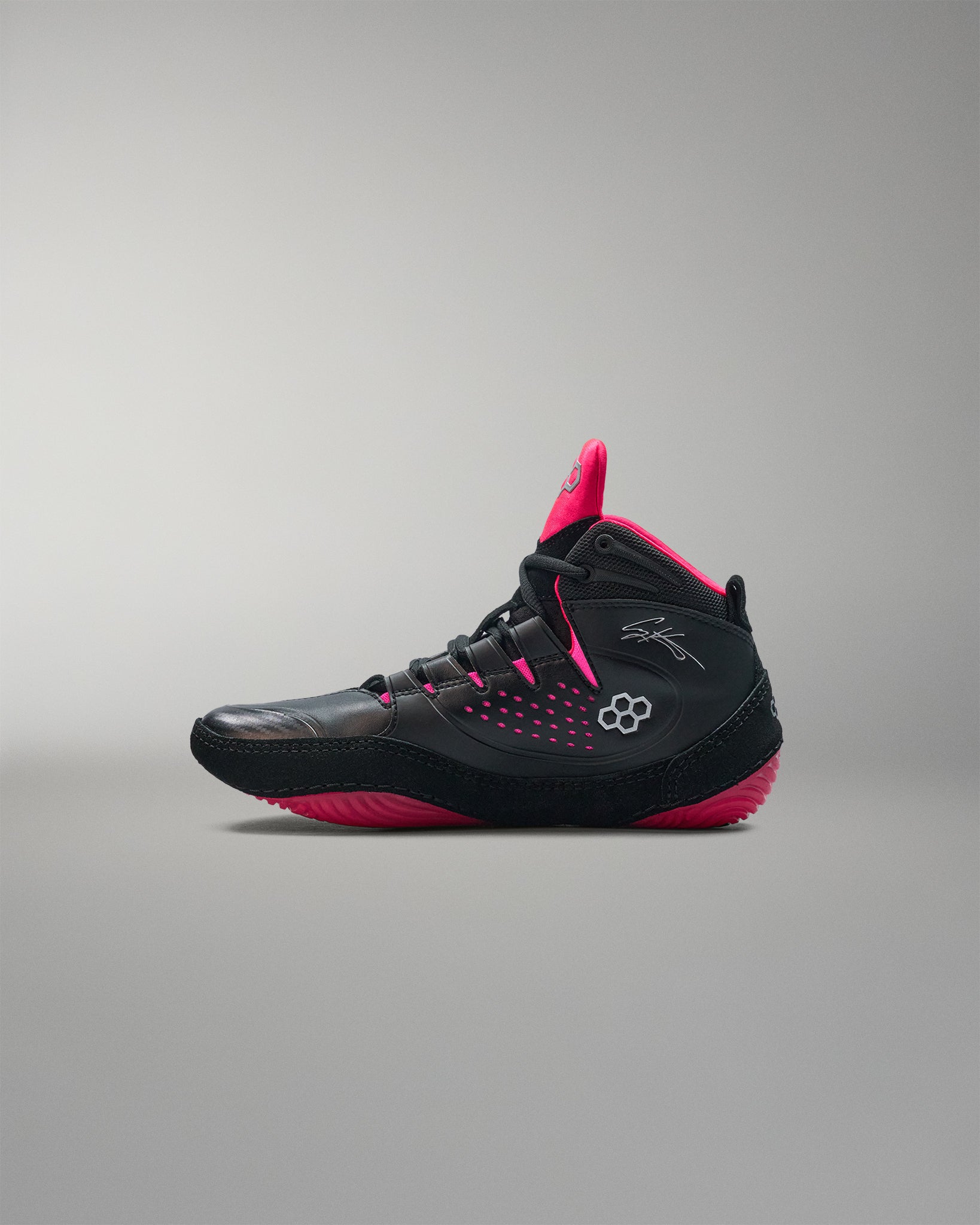 Black and pink wrestling shoe on a gray background