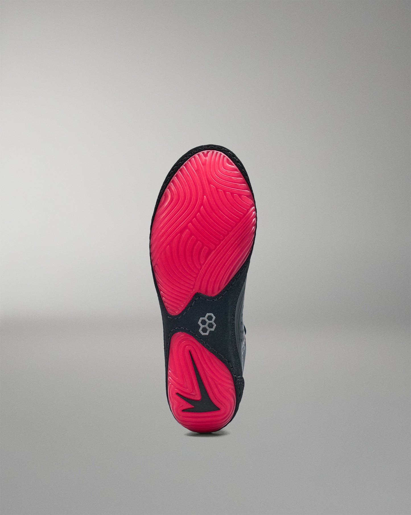 Black and pink sole of a wrestling shoe on a gray background