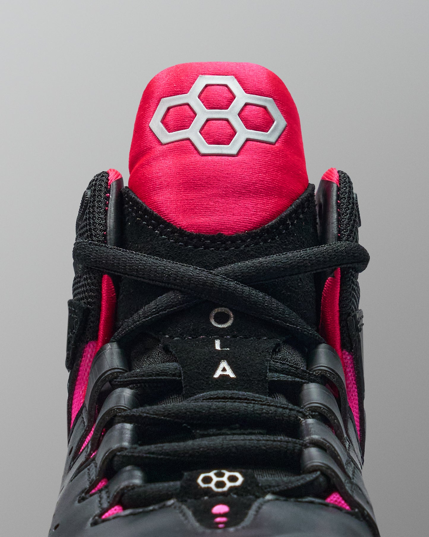Black and pink wrestling shoe with a prominent brand logo on a gray background