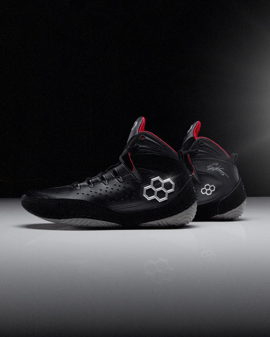 Black wrestling shoes with red accents on a dark background