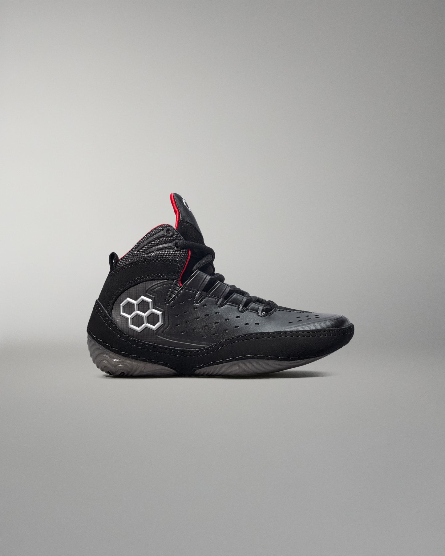 Black wrestling shoes with a red accent on a gray background