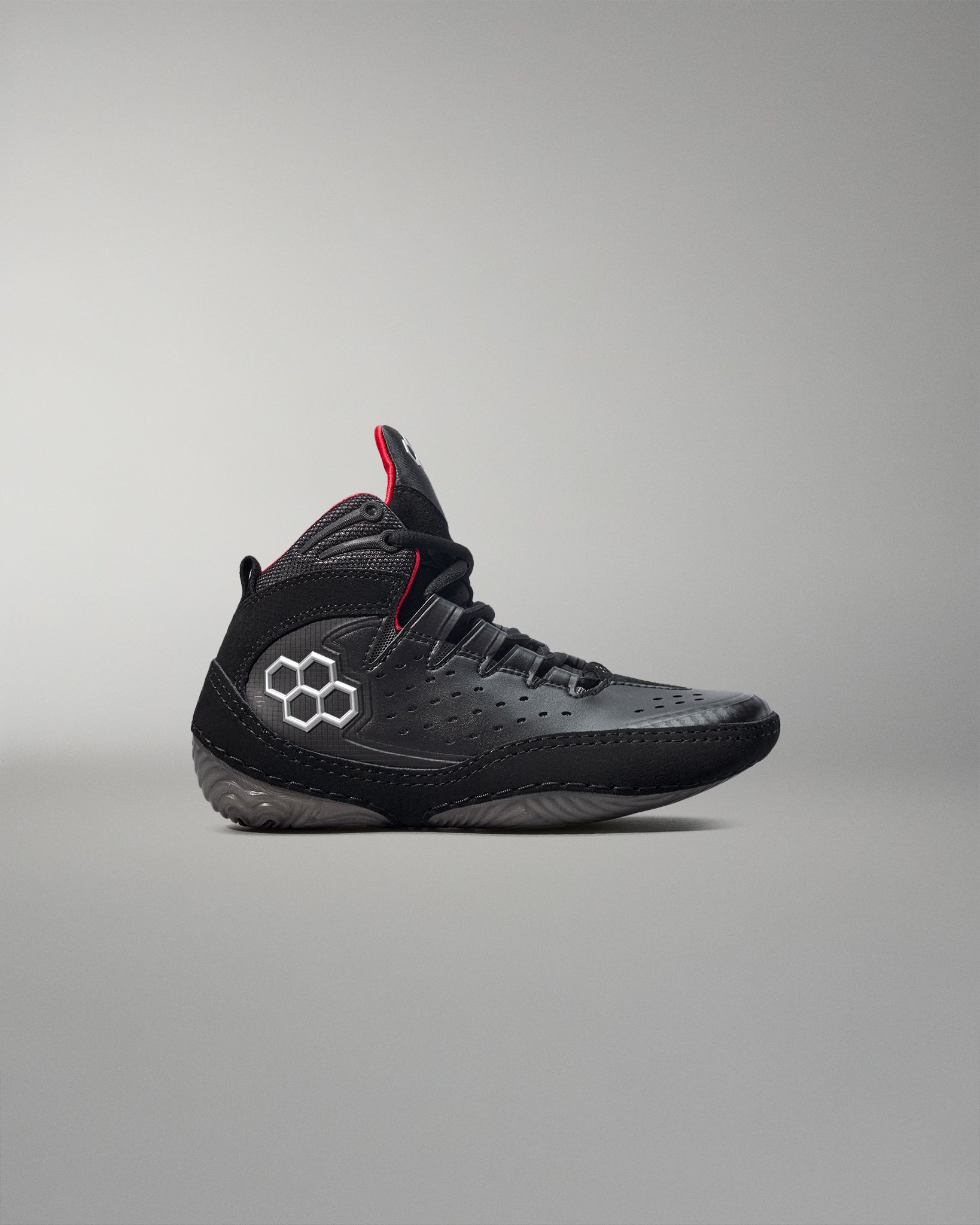 Black wrestling shoes with a red accent on a gray background