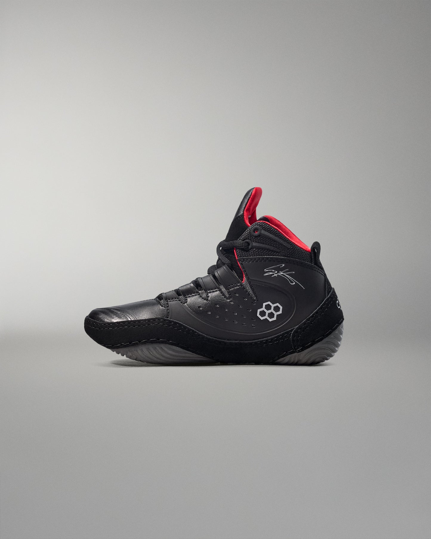Black wrestling shoes with red accents on a gray background