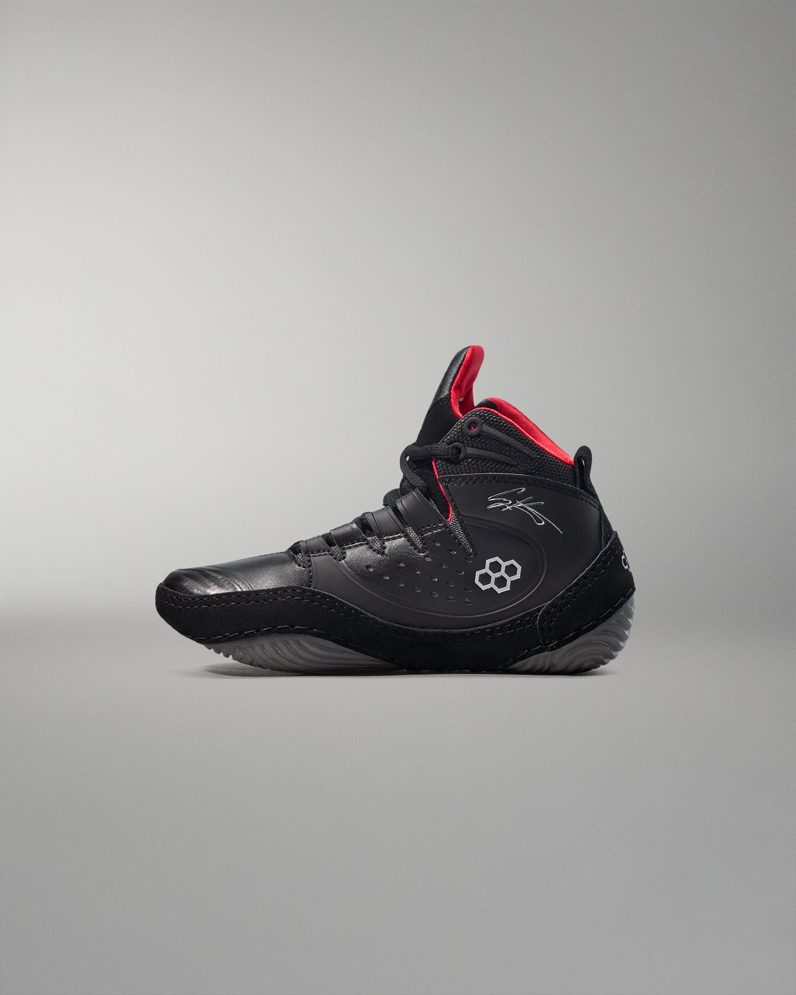 Black wrestling shoes with red accents on a gray background