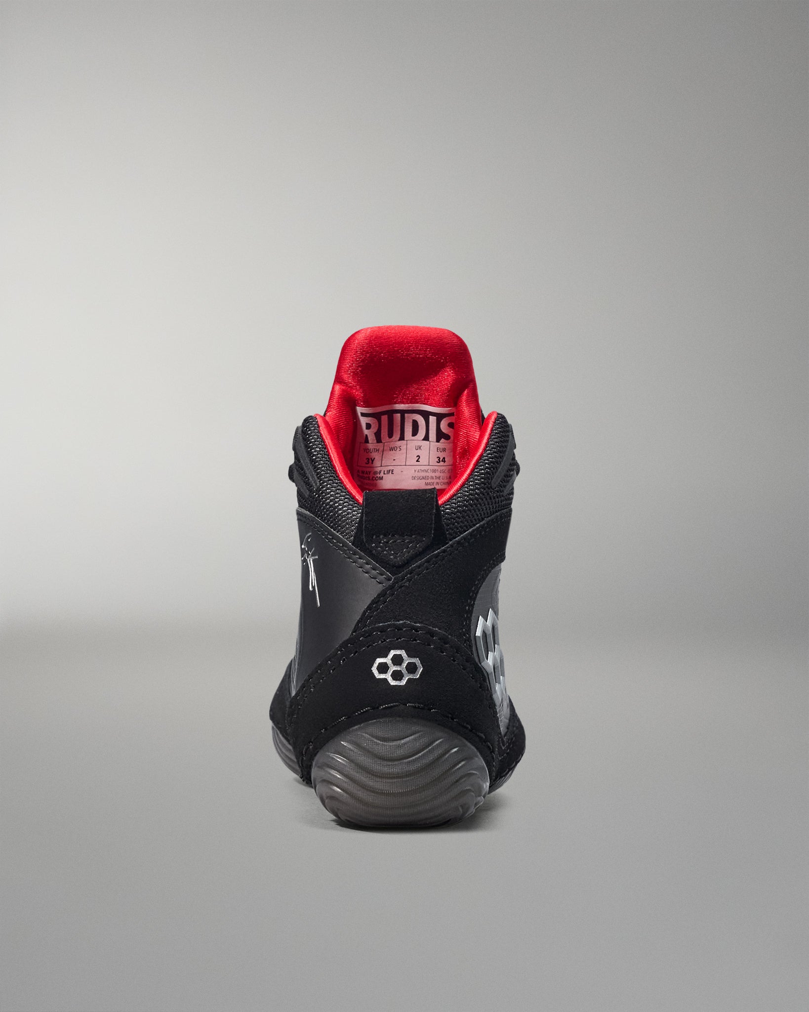 Black wrestling shoe with red lining on a gray background