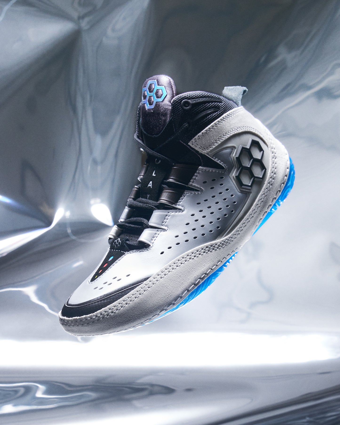 White and black wrestling shoe with blue accents on a reflective silver background