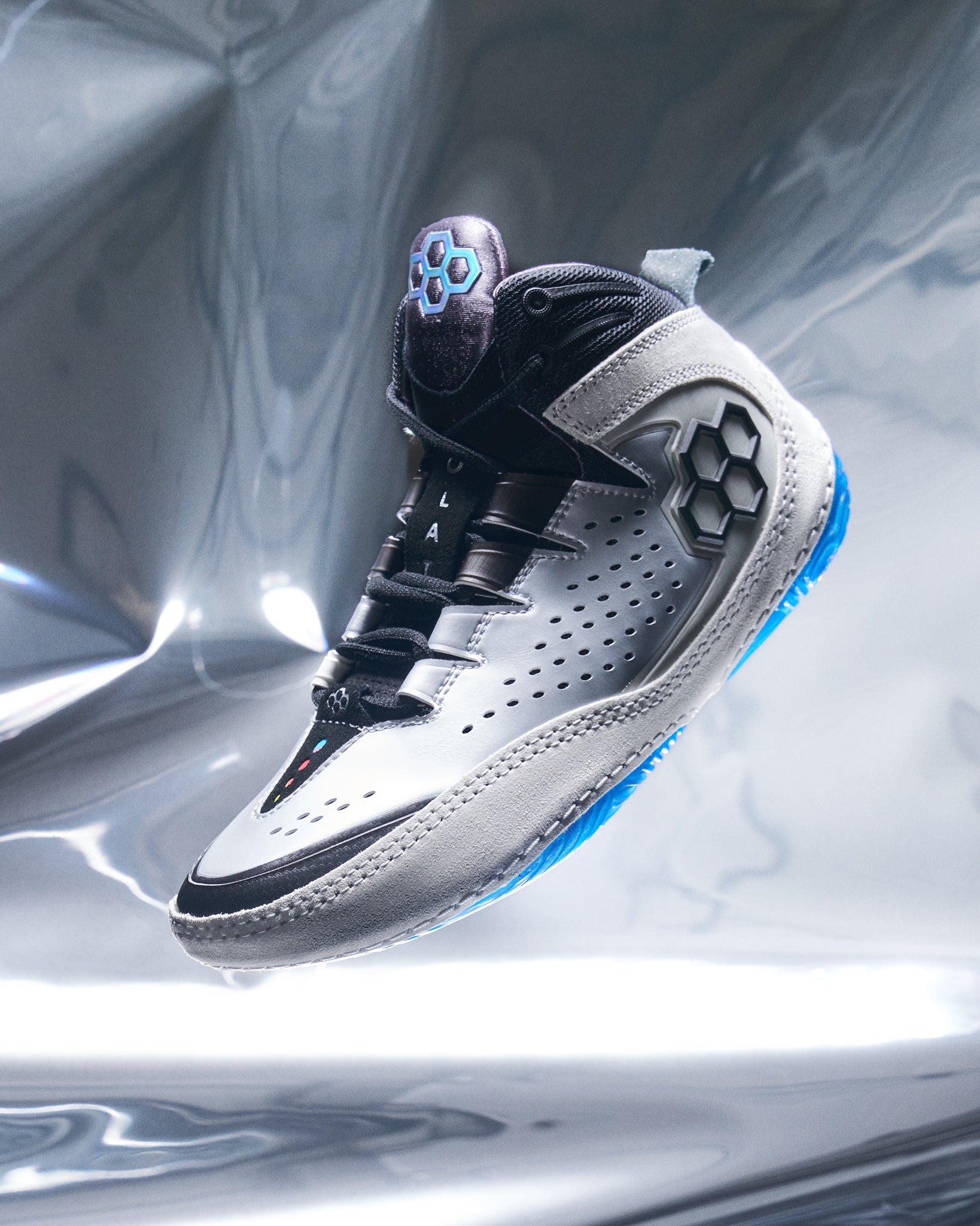 White and black wrestling shoe with blue accents on a reflective silver background