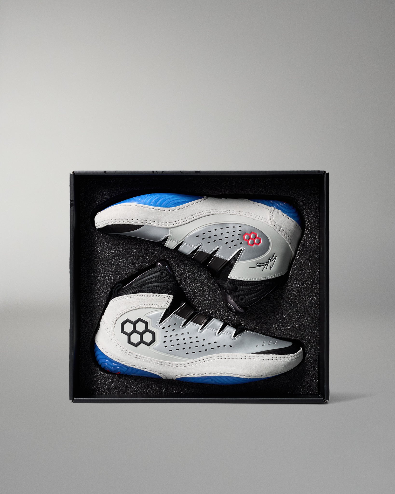 White and blue wrestling shoes in a black box on a gray background