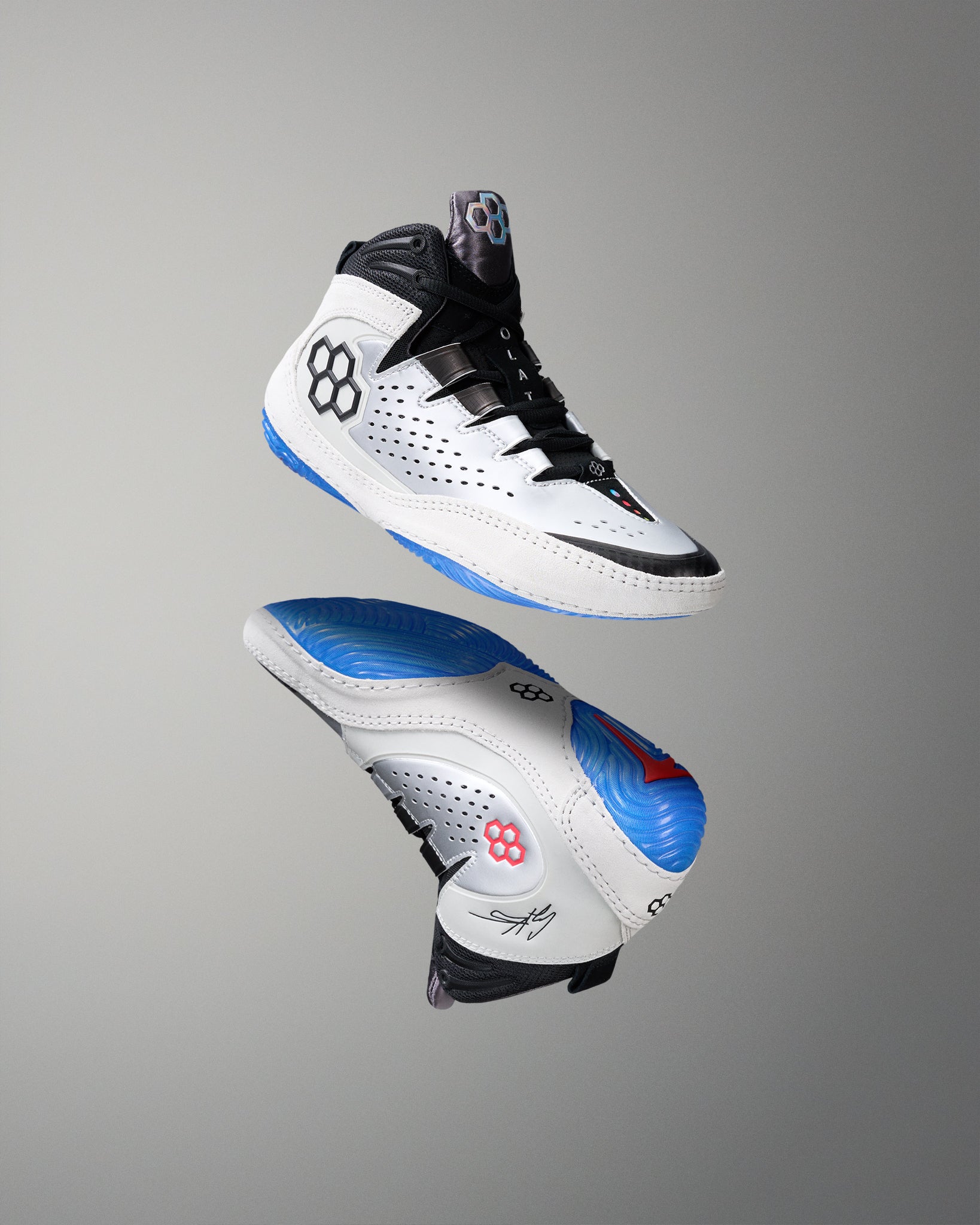 Pair of white wrestling shoes with black and blue accents on a gray background