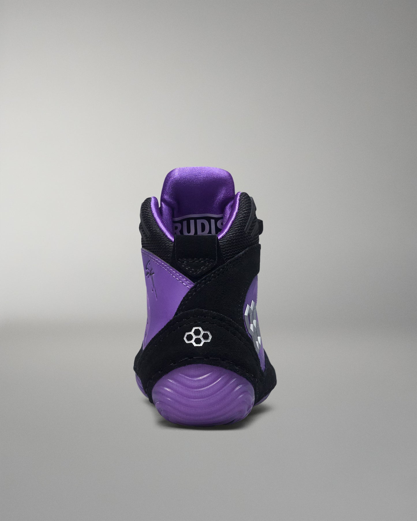 Purple and black wrestling shoe with 'RUDIS' branding on a gray background