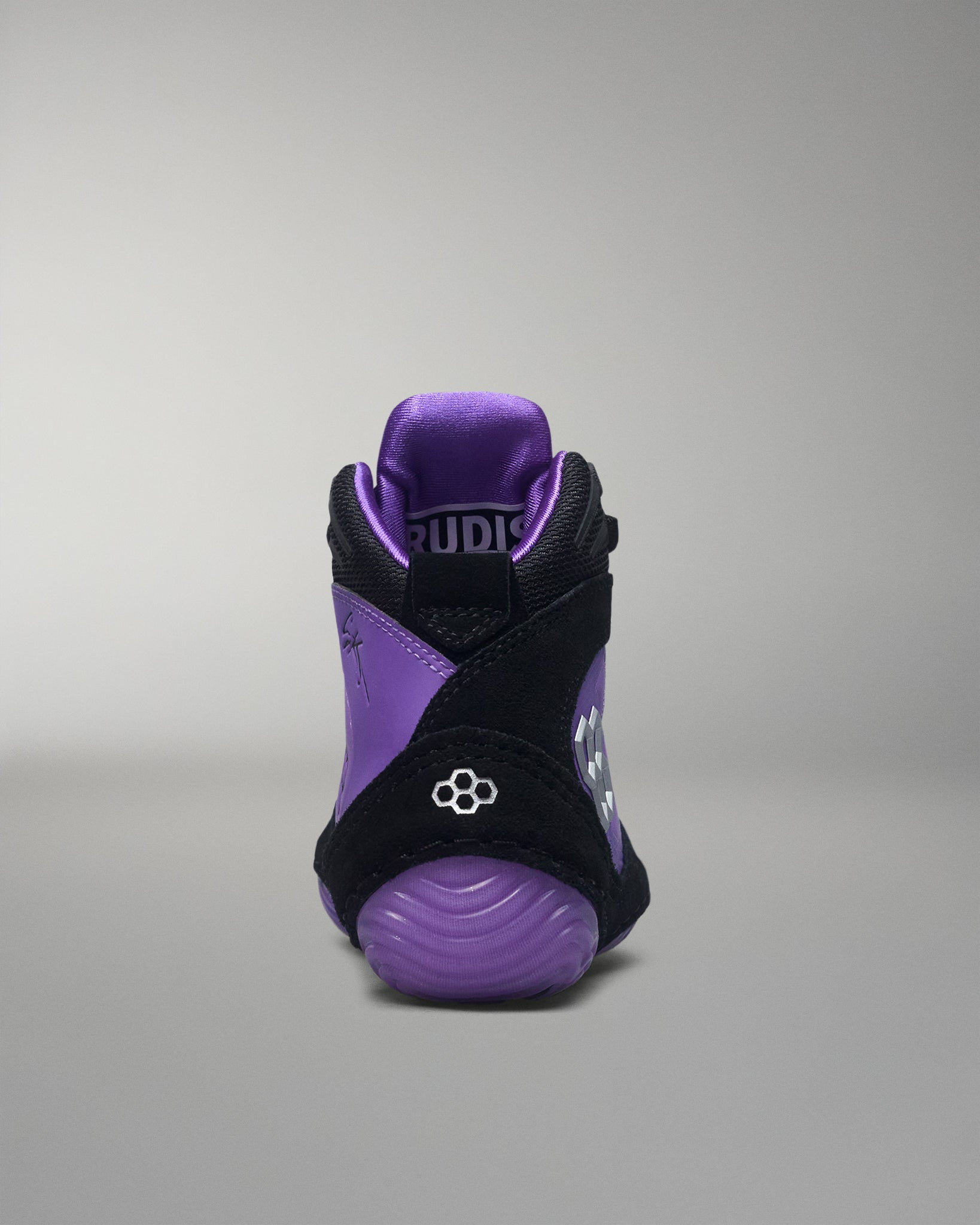 Purple and black wrestling shoe with 'RUDIS' branding on a gray background