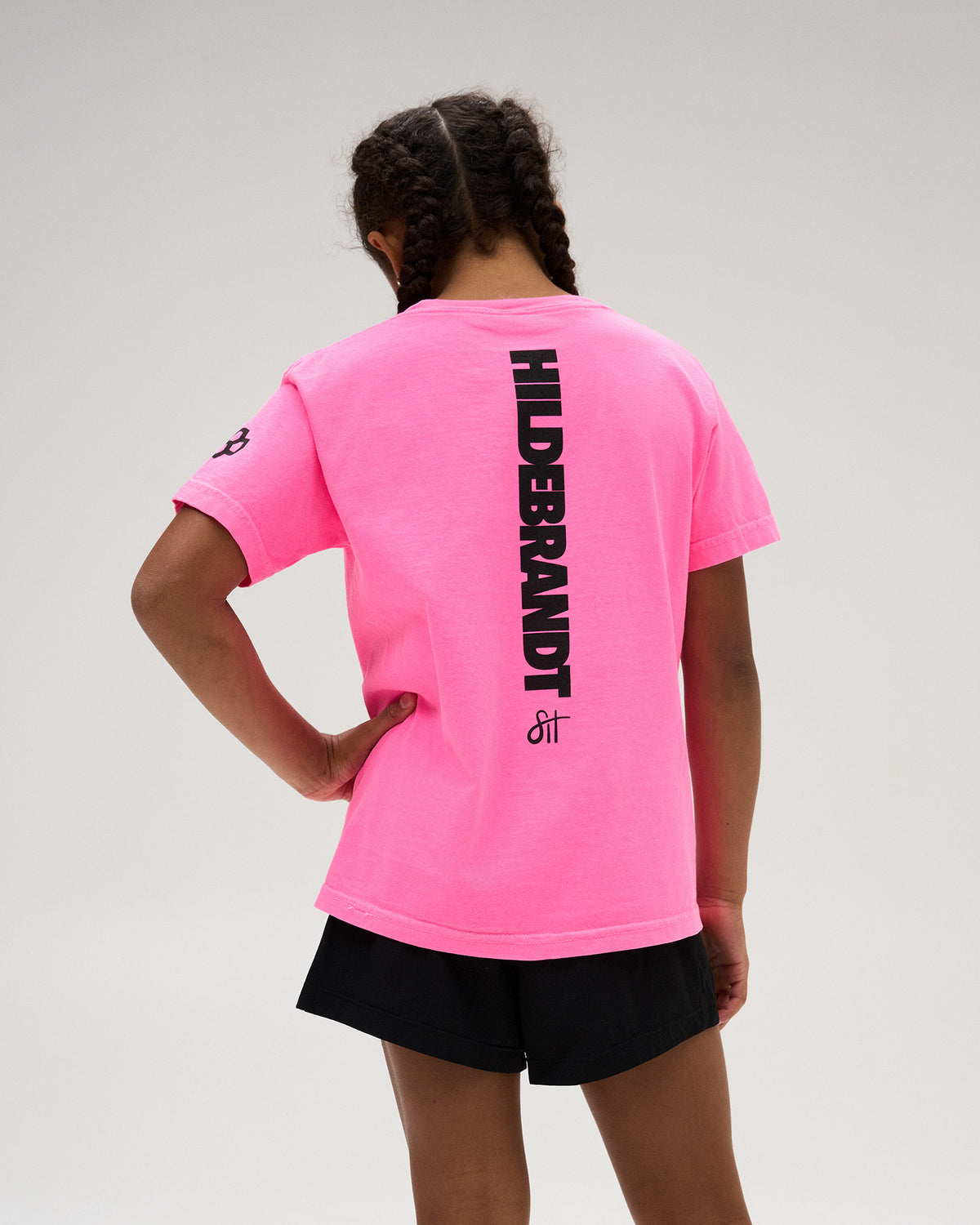 RUDIS Sarah Hildebrandt Bolt Neon Youth Heavyweight T-Shirt in Neon Pink, featuring vertical “HILDEBRANDT” graphics with Sarah Hildebrandt signature detailing down the back.