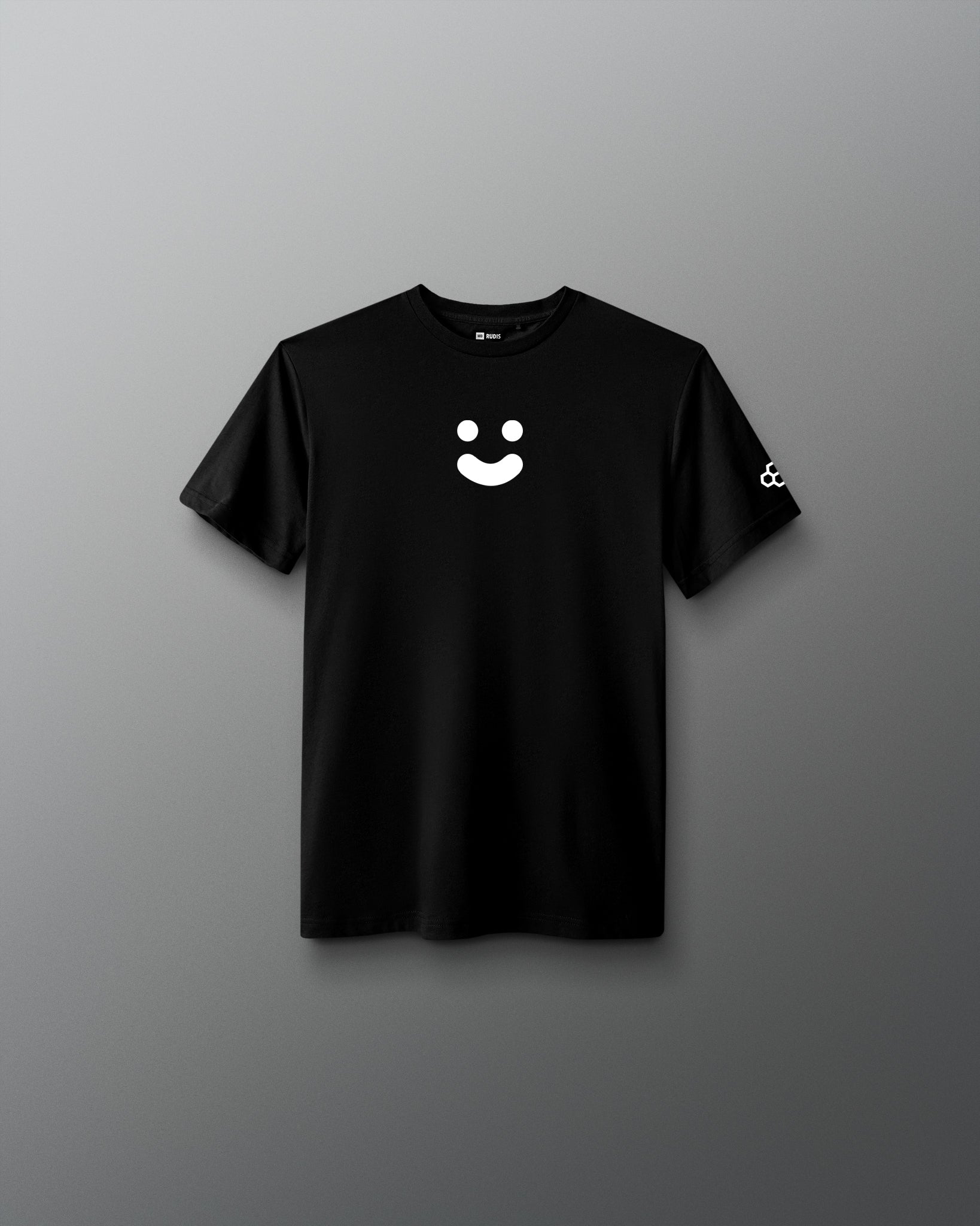 A black short-sleeve crewneck t-shirt featuring a white minimalist smiley face graphic on the center chest and a small white logo on the left sleeve, displayed against a neutral gray gradient background.