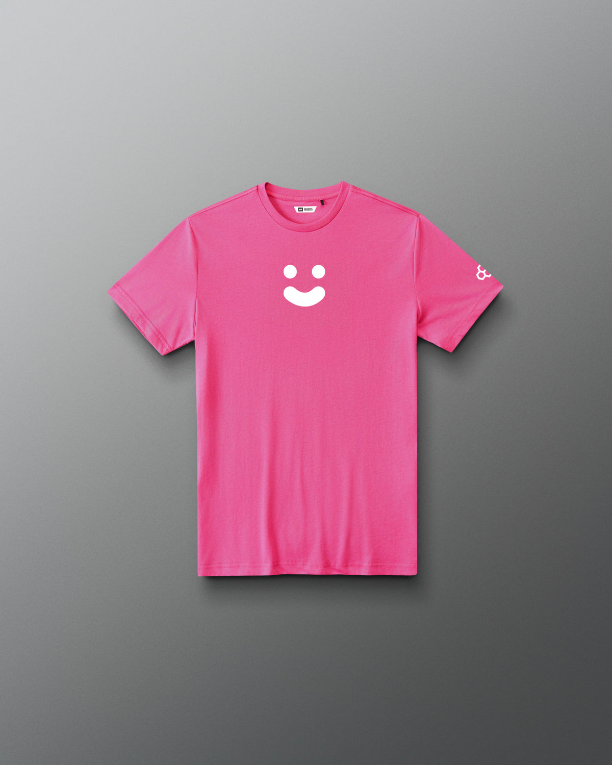 A bright pink short-sleeve t-shirt with a white minimalist smiley face graphic on the center chest and a small white logo on the left sleeve, displayed flat against a dark gray gradient background.