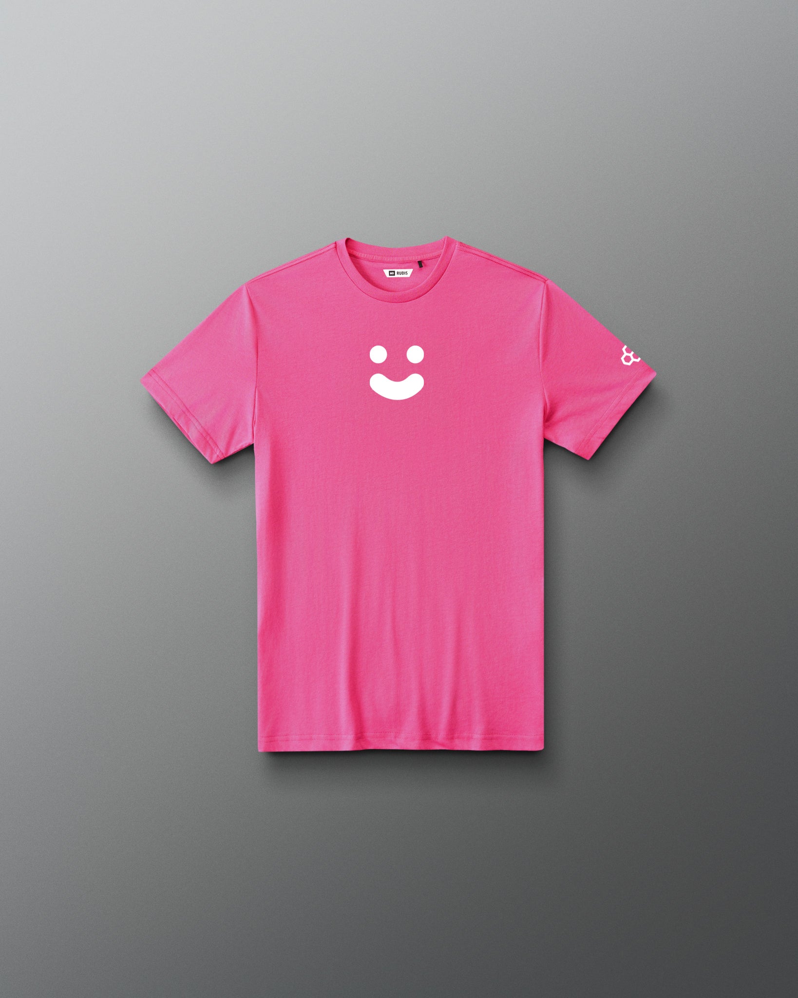 A bright pink short-sleeve t-shirt with a white minimalist smiley face graphic on the center chest and a small white logo on the left sleeve, displayed flat against a dark gray gradient background.