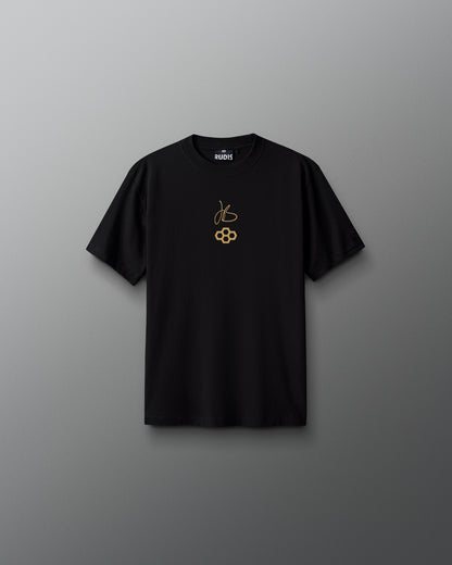Black RUDIS Youth JB Gold Heavyweight T-Shirt shown from the front, featuring Jordan Burroughs’ signature and RUDIS mark in gold on the chest with a tonal RUDIS sleeve logo.