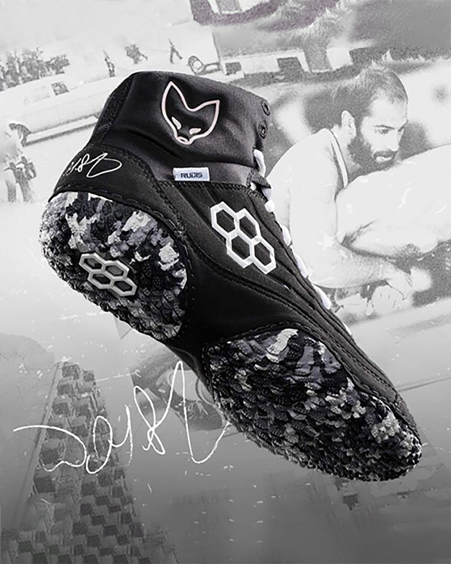 A dynamic black athletic shoe with a unique hexagonal grip pattern on the sole and a distinctive fox logo on the side set against a stylized grayscale background featuring an action shot of a wrestler highlighting the shoes performance features