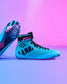 RUDIS Godzilla Samurai Speed Youth Wrestling Shoes in bright blue with black laces, Godzilla ankle strap, and graphic outsole displayed against a blue and pink gradient background.
