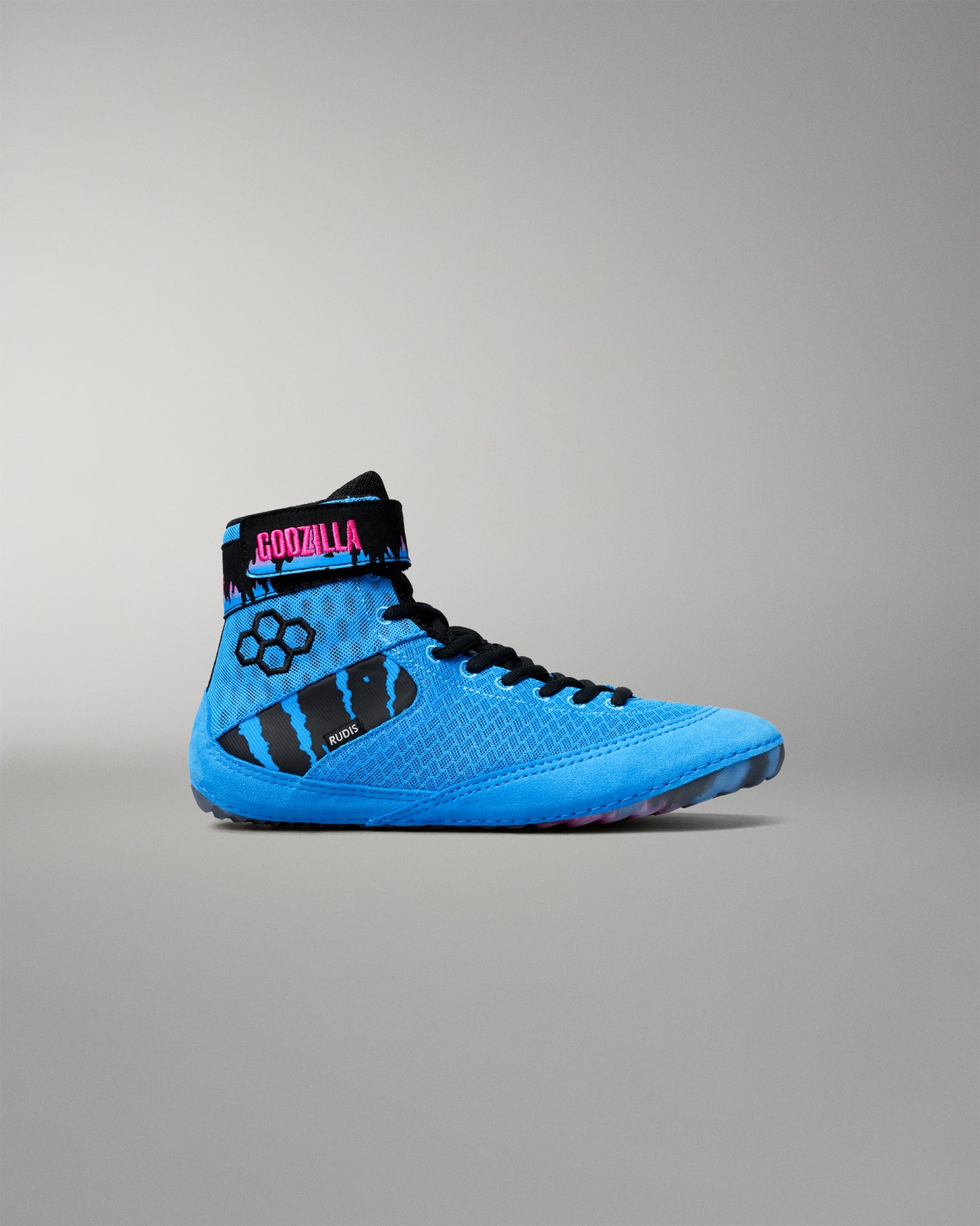 A high-top wrestling shoe in bright blue and black, featuring a textured knit upper, black laces, a black ankle strap with a pink and blue 'Godzilla' logo, and a black paw print graphic on the side, shown against a neutral gray background.