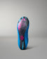 The outsole of a wrestling shoe is shown from the bottom, featuring a vibrant blue and black patterned design with a pink logo in the center.