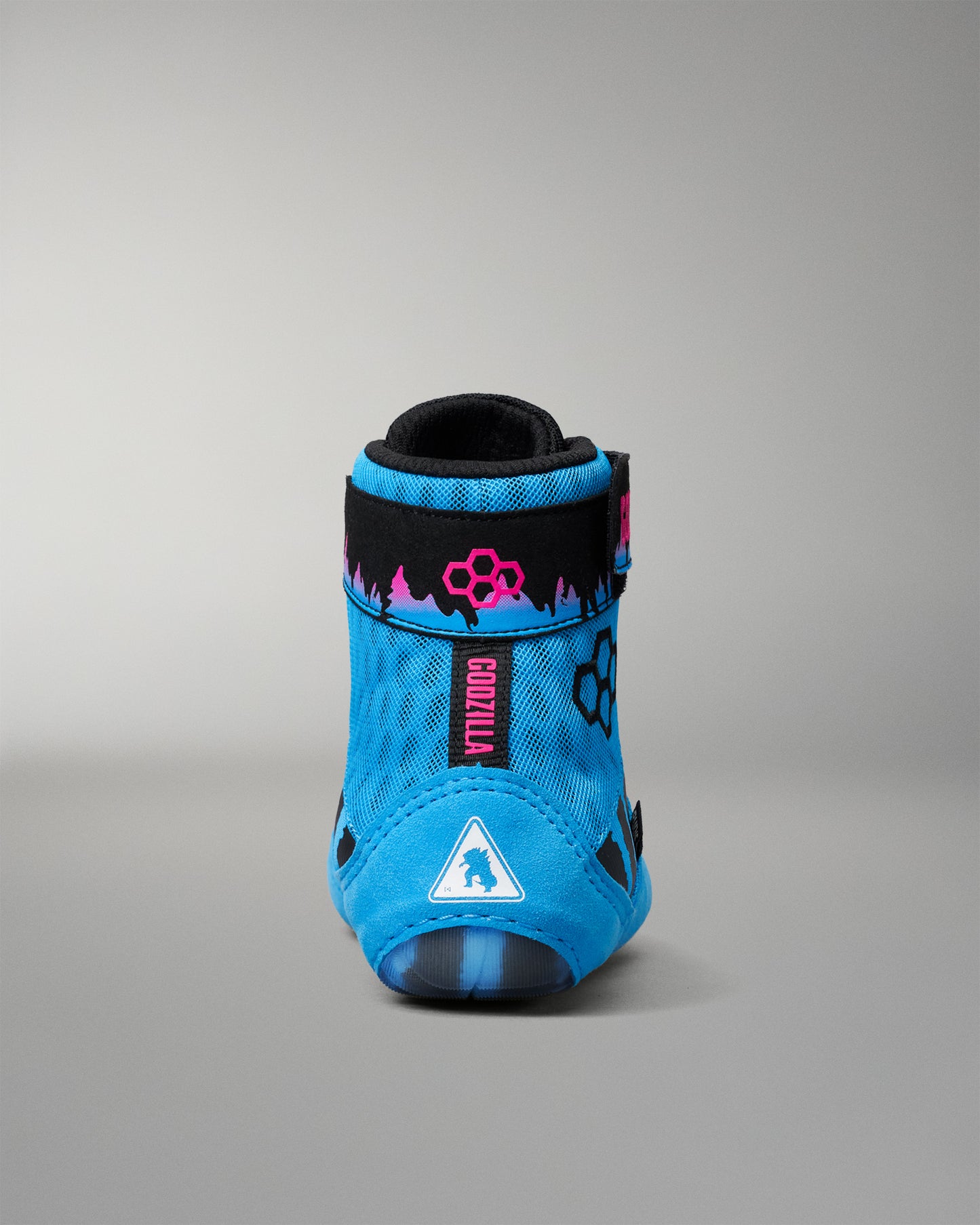 A single high-top wrestling shoe shown from the back on a neutral gray studio background. The boot is primarily bright blue with black trim, a black strap, and pink graphic details, including a visible 'Gorilla' brand tag.